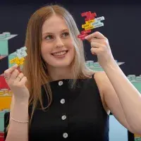 ECA graduate Katie Marsden poses with Lego kits she created deigned to help people with Down's Syndrome learn about consent.