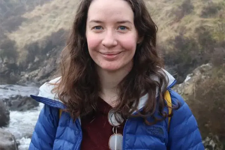 Claire Hobday smiling in front of outdoor scenic background. 