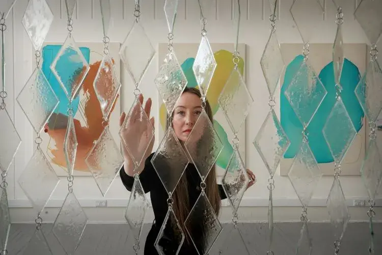 Sculpture student Kristel Bodensiek approaches her work Tide and Temper, a calming curtain made of glass and steel.