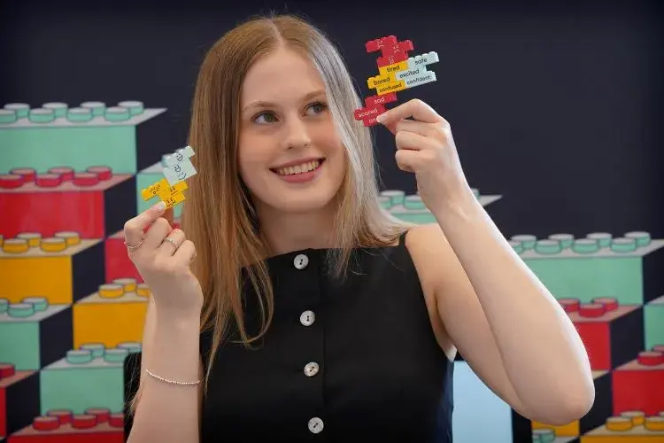 ECA graduate Katie Marsden poses with Lego kits she created deigned to help people with Down's Syndrome learn about consent.