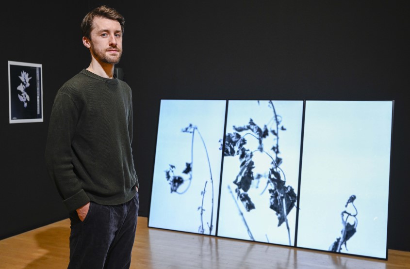 Image of Matt Zurowski in front of his artwork on display at the Talbot Rice Gallery